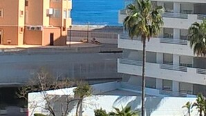 A high-rise building with multiple balconies overlooking a beach.