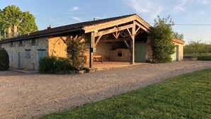 A rustic stone building with a wooden porch and a gravel driveway. - Charming farmhouse with private pool in secluded location.  (Monteton)