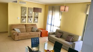 A living room with two sofas, a glass dining table, and a modern pendant light. - Beautiful duplex apartment with pool 200 meters from the beach and golf (el campello muchavista)