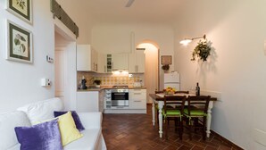 A compact living space with a kitchenette, dining area, and a sofa with cushions.