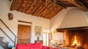A cozy living room with a wooden ceiling, a fireplace, a red sofa, and a wooden coffee table.