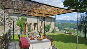 A table set outdoors with a view of a stone building and a grassy landscape.