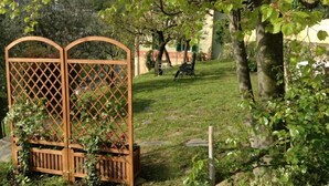Ein Garten mit Holzlattenzaun, einer grünen Rasenfläche und einem Baum mit Blättern.