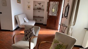 Ein Zimmer mit zwei Sesseln, einer Holztür mit dekorativen Glasfeldern und einem Fliesenboden.