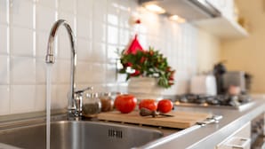 A modern kitchen with a stainless steel sink, a wooden cutting board, and fresh tomatoes.