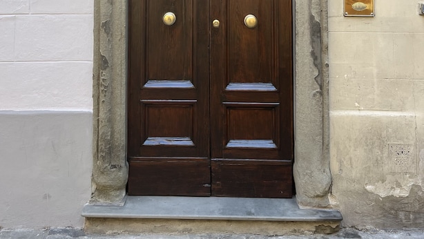 A double wooden door with a stone arch and a shield emblem above it.