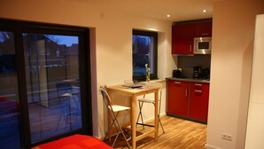 A compact room with a bed, a small desk with a chair, a microwave, and a refrigerator. - City-Apparte One - Modern apartment building in a central location (Gronau)