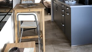 A compact kitchen with a microwave, stove, and sink. There is a dining area with a chair and a table. - City-Apparte One - Modern apartment building in a central location (Gronau)
