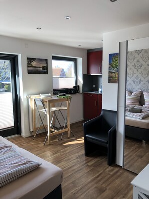 Un espace de vie compact comprenant une kitchenette, un coin repas et une chambre.