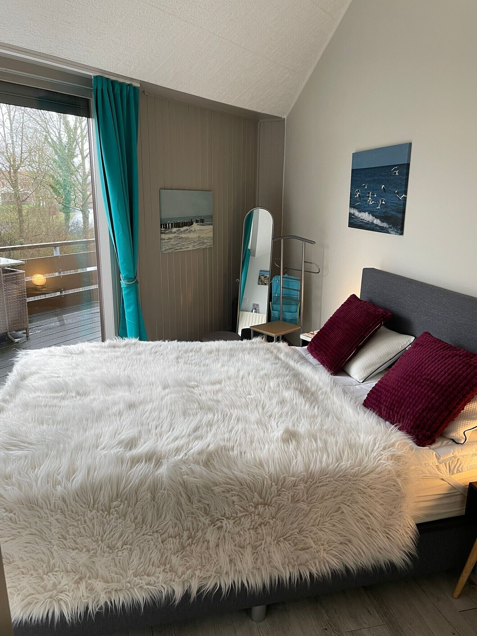 Een ruime slaapkamer met een groot bed, uitzicht op het landschap via een schuifdeur, een klein nachtkastje en een nachtkastje.