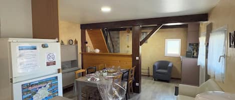 A kitchen with a refrigerator, a table with a plastic bag of food, and a microwave.
