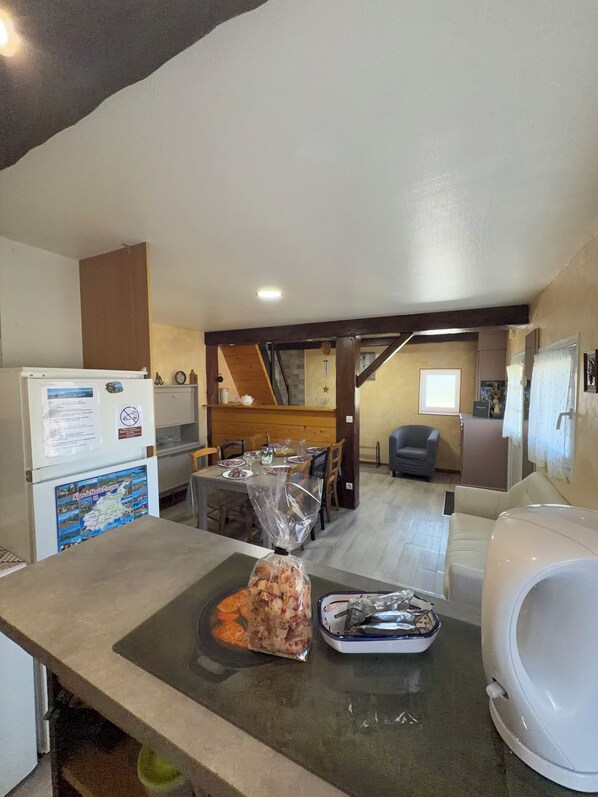 A kitchen with a refrigerator, a table with a plastic bag of food, and a microwave. - Between Lakes and Mountains (Saint-Vincent-Les-Forts)