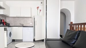 Un espacio habitable compacto con kitchenette, lavadora, comedor y sofá.