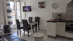 Una cocina moderna con comedor, televisor montado en la pared y un reloj.