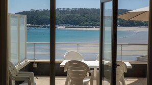 Un balcon donnant sur une plage, avec une table et des chaises.