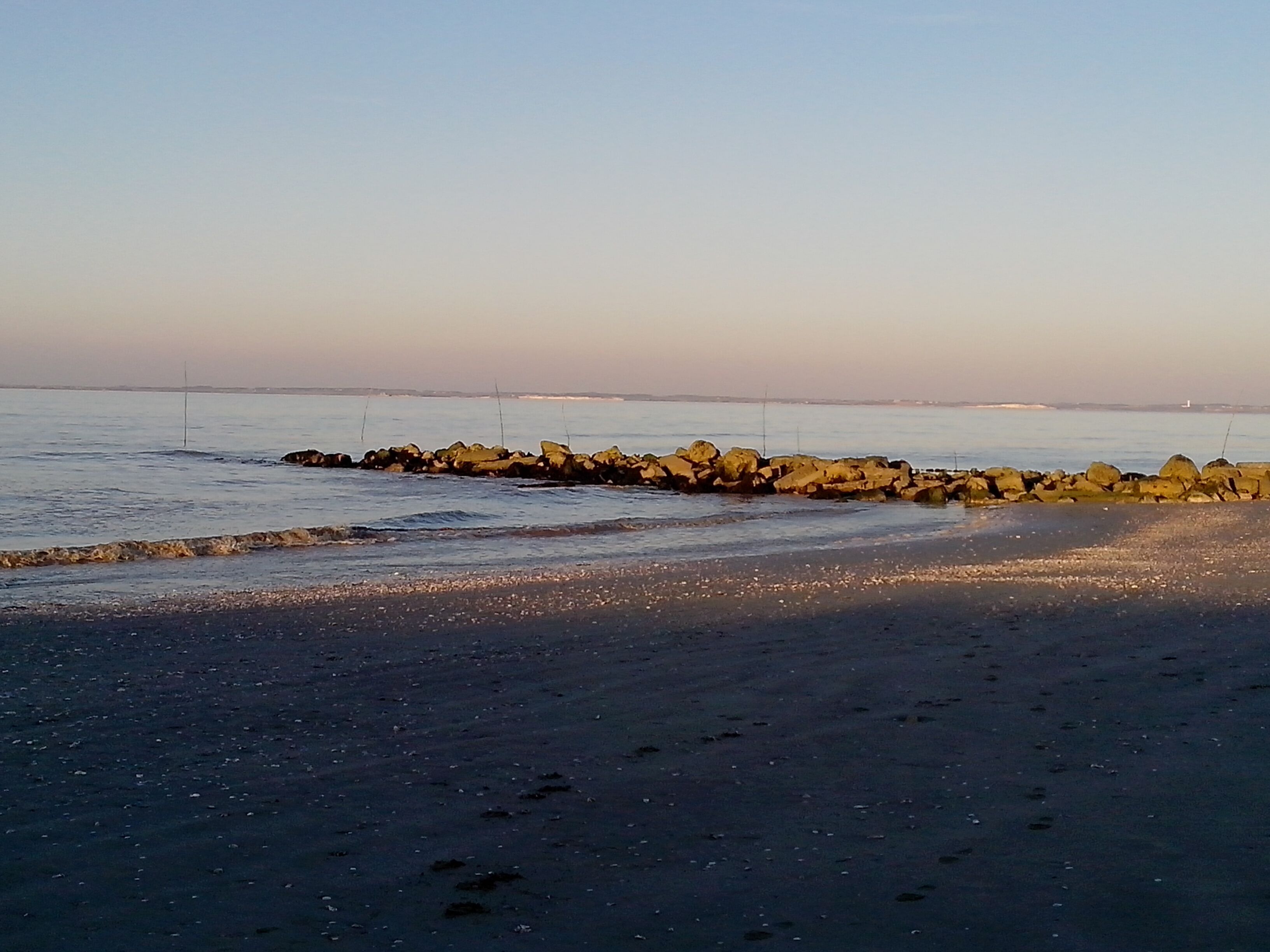 En strand med en molerude og roligt vand.