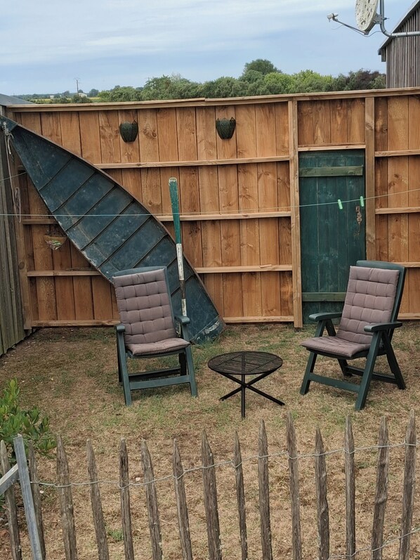 Un patio trasero cercado con dos sillas y una mesita.