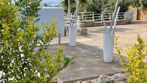 An outdoor patio area with stone flooring, white pillars, and a metal railing. - Modern villa for 1 to 6 people, private pool, beautiful sea and mountain views (Crete)