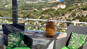 A terrace with wicker furniture, green cushions, and a view of the sea and hills. - Modern villa for 1 to 6 people, private pool, beautiful sea and mountain views (Crete)