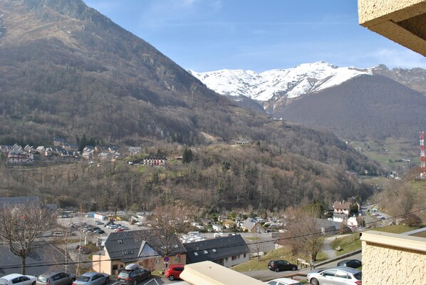 A mountain village with snow-capped peaks, a parking lot, and residential buildings. - RESIDENCE LE RIOU (Cauterets)