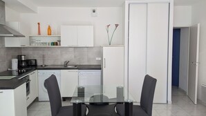 A modern kitchen with white cabinets, a glass-top dining table, and black chairs.