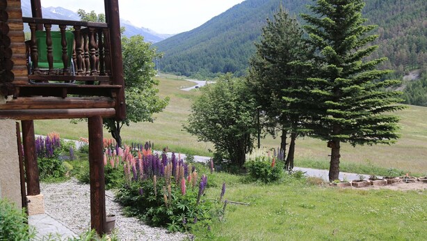 A wooden balcony with a view of a mountainous landscape, a garden with colorful flowers, and a clear sky. -  Appart 3 ch 6 Pers comfortable 3 * in the cottage Laget (Molines-En-Queyras)