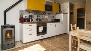 A modern kitchen with white and yellow cabinets, a built-in oven, and a wood-burning stove. -  Appart 3 ch 6 Pers comfortable 3 * in the cottage Laget (Molines-En-Queyras)