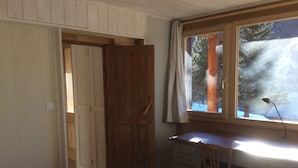 A bedroom with a bed, a desk with a chair, a dresser, and a window with a view of trees. -  Appart 3 ch 6 Pers comfortable 3 * in the cottage Laget (Molines-En-Queyras)