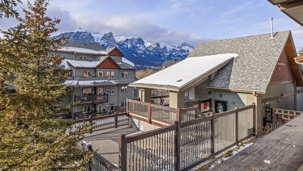 Ein Gebäude mit einer Holzterrasse und Blick auf verschneite Berge im Hintergrund.