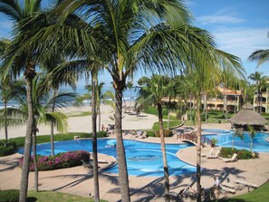 Ein Resort mit großem Schwimmbad, Palmen und einem Strand.