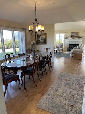 A spacious living room with a fireplace, a dining area with wooden furniture, and large windows offering a view of greenery. - Lavender Hill Ranch Santa Ynez: 7 Acre Estate Epic Hilltop Views Near Shops/Wine (Solvang)