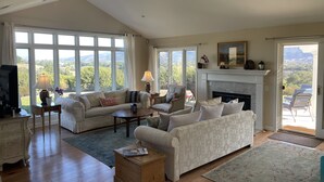 Un salon spacieux doté d’une cheminée, de grandes fenêtres offrant une vue panoramique et d’un coin salon confortable.