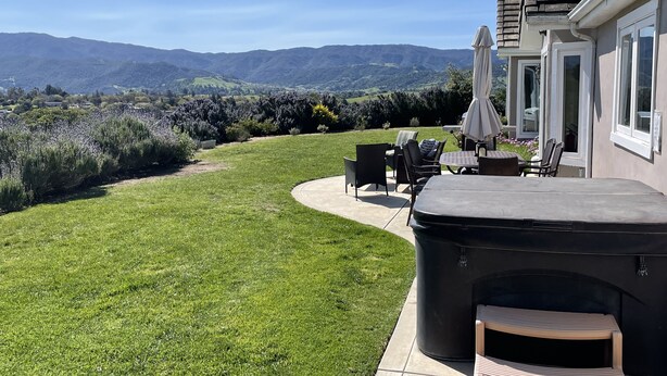 Une terrasse avec mobilier d’extérieur, un barbecue et une vue sur un paysage vallonné.