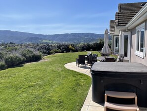 Une terrasse avec mobilier d’extérieur, un barbecue et une vue sur un paysage vallonné.