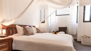 A bedroom with a canopy bed, wooden headboard, white bedding, and a bedside lamp. - ❤ Exceptional oceanfront vacation ✔ (Kralendijk (Punt Vierkant))