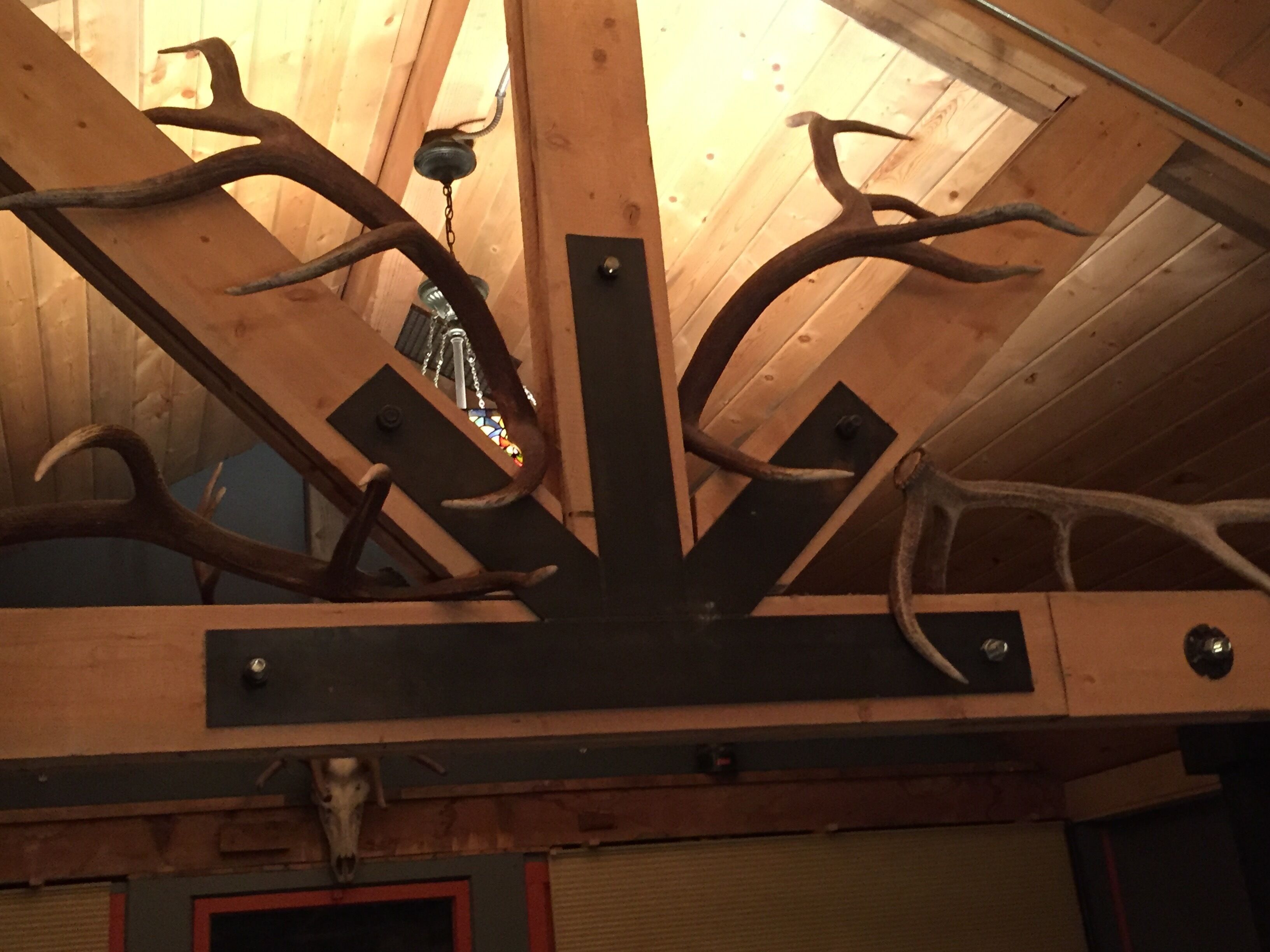 A ceiling with wooden beams and antlers.