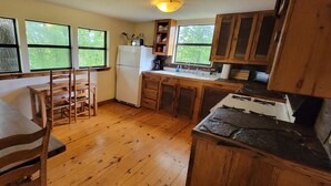 Una cocina con armarios de madera, un refrigerador y un comedor con mesa y sillas.