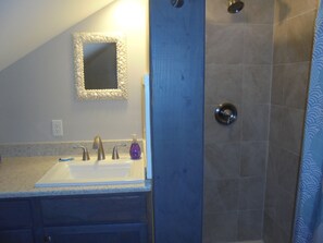 A bathroom with a sink, mirror, and shower. - Relaxing resort home, newly renovated (Edisto Island)