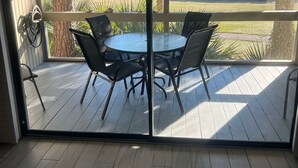 Ein Zimmer mit einer Schiebetür und Zugang zu einer Terrasse mit einem runden Tisch und Stühlen.