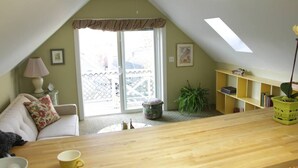 A cozy room with a wooden table, a sofa, a bookshelf, and a window with a view. - Adorable Portland getaway on the Eastern Promenade (Portland)