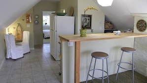 A kitchen with a wooden island, two stools, a refrigerator, and a hanging light fixture. - Adorable Portland getaway on the Eastern Promenade (Portland)