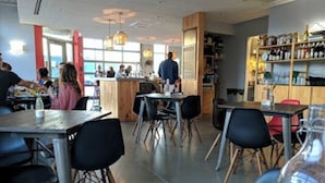 A restaurant interior with tables and chairs, a bar area, and shelves with bottles. - Adorable Portland getaway on the Eastern Promenade (Portland)
