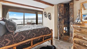 Un dormitorio con una cama grande, una chimenea de piedra y vistas a las montañas.