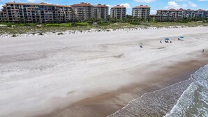 Ein Strand mit einer Reihe mehrstöckiger Gebäude im Hintergrund.