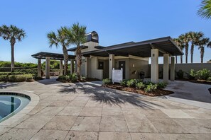 A pool area with a covered seating area, palm trees, and a sign indicating pool rules. - NEW PHOTOS! Stylish, Fully Renovated Sea Dunes Condo on Ground Floor! (Fernandina Beach)