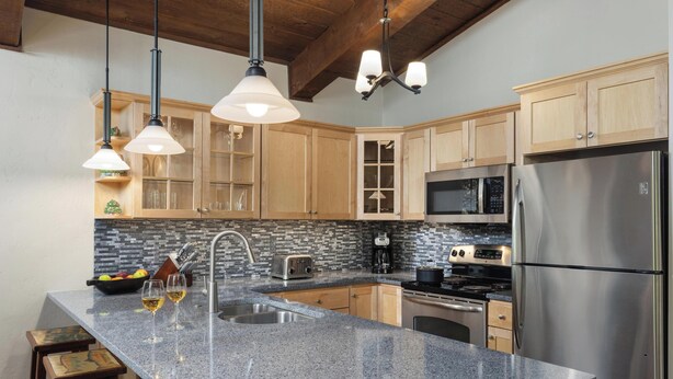 A kitchen with granite countertops, wooden cabinets, stainless steel appliances, and pendant lighting. - Top of the Village~Ski-in/out~HT~Pool~Grill~Parking (Snowmass Village)