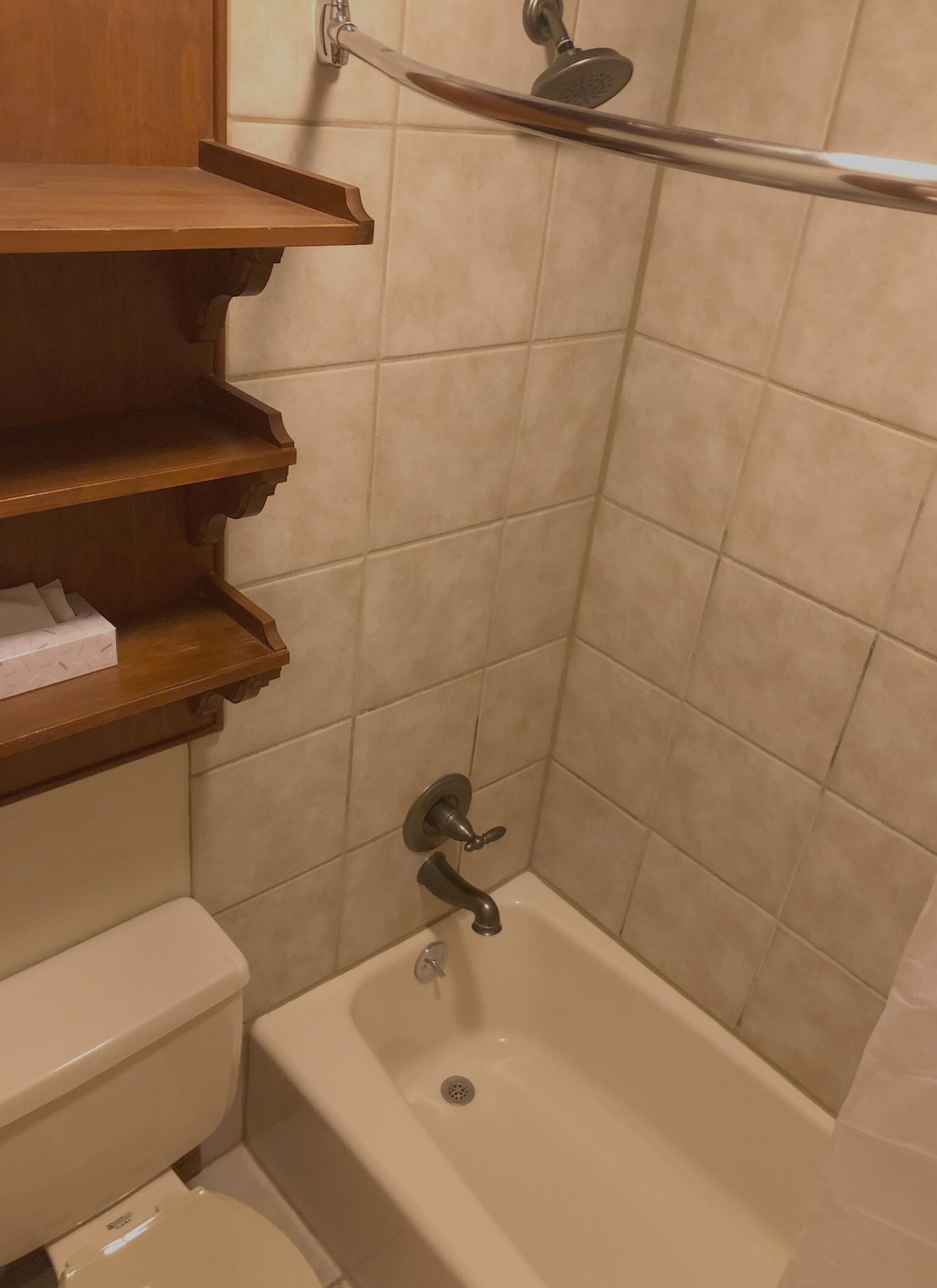 Un baño con bañera, inodoro y un estante con artículos de aseo.