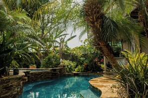 Una piscina privada rodeada de exuberante vegetación tropical y muros de piedra.