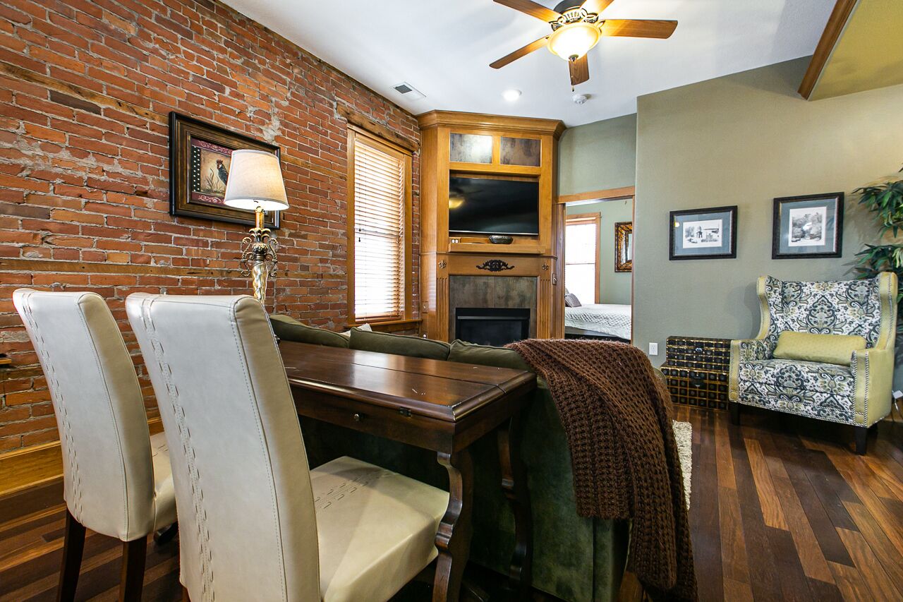 A dining area with a brick wall, wooden dining table, and chairs.