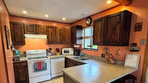 Una cucina con mobili in legno, un forno bianco, un microonde e una grande isola con sgabelli.